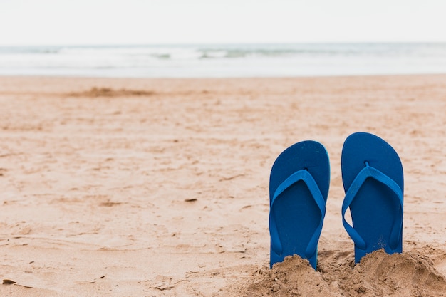 Beach concept with flip flops in sand