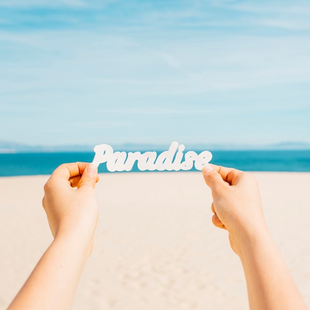 Free Photo beach concept with hands holding paradise letters