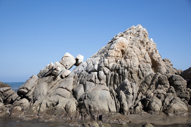 Beach covered in rocks surrounded by the sea under the sunlight and a blue sky in Mexico