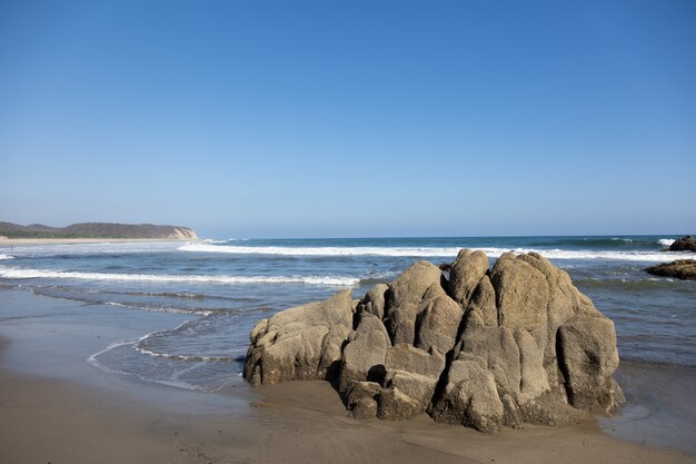 Beach surrounded by the sea and rocks under the sunlight and a blue sky in Mexico