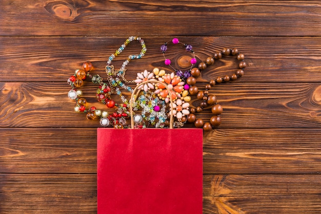 Free photo beads jewelry and red paper bag on wooden background