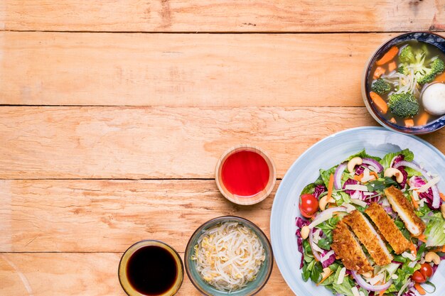 Bean sprouts; soup; fillet; salad with sauces on wooden desk