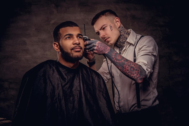 Free Photo bearded african american hipster guy getting a haircut by an old-fashioned tattoed professional hairdresser does the haircut.