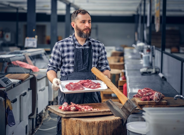 Free photo bearded butcher dressed in a fleece shirt serving fresh cut meat in a market.