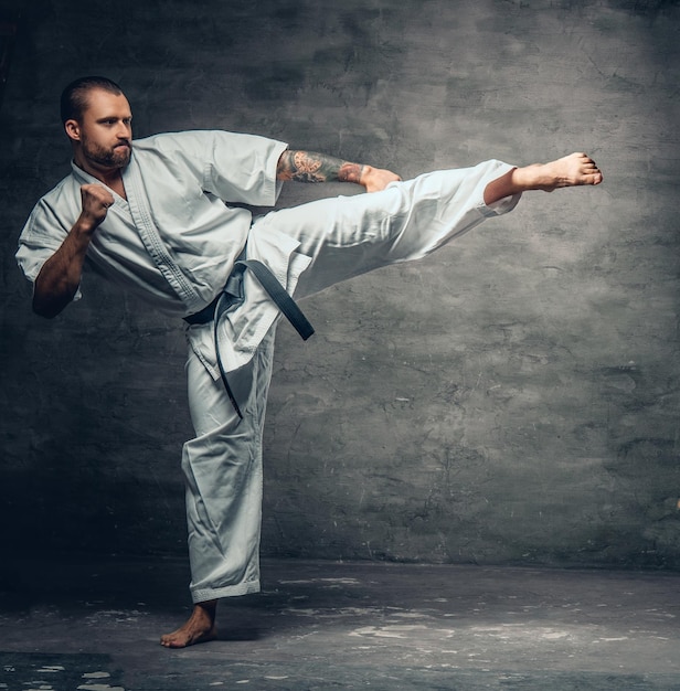 Free photo bearded karate fighter dressed in a white kimono in action.