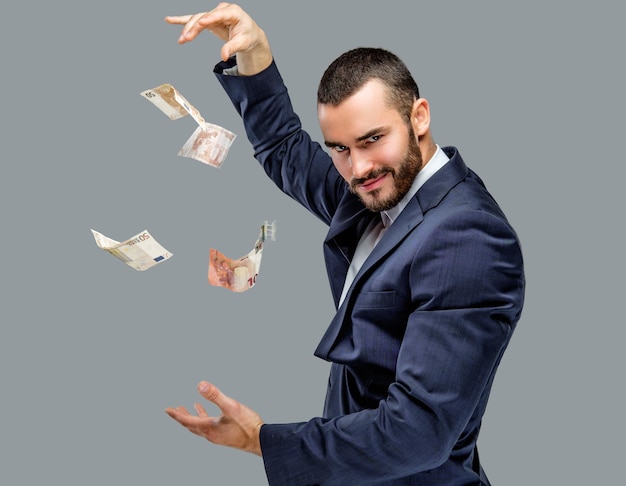 Free photo bearded male in a suit holding cash money isolated on grey background.