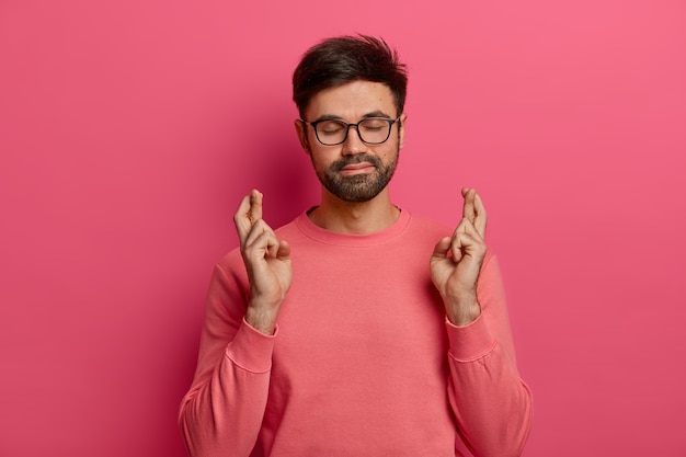 Free photo bearded man crosses fingers, expresses willingness, wants to fulfill wish