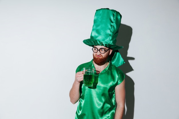 Free photo bearded man in green costume and eyeglasses holding cup