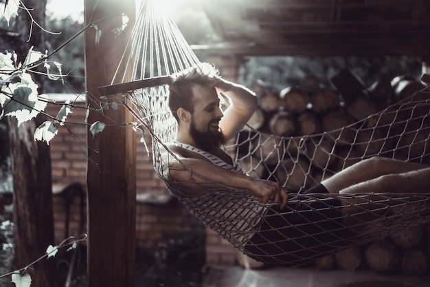 Free Photo bearded man lying hammock on a warm summer day