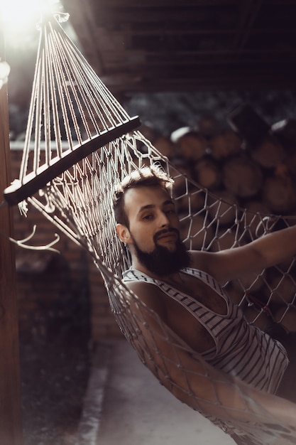 Free photo bearded man lying hammock on a warm summer day