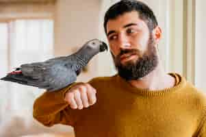 Free photo bearded man petting cute bird