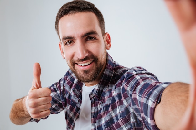 Bearded man in shirt making selfie and showing thumb up