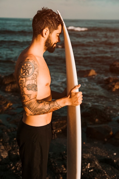 Free Photo bearded man with surf board on shore near water 