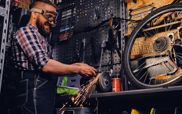 Free Photo bearded mechanic cutting and polish bike part in a workshop.