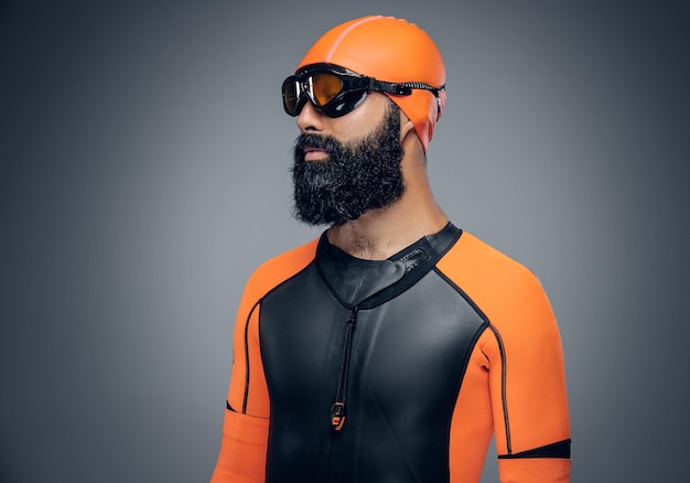 Free photo bearded scuba diver male in orange neoprene suit isolated on grey background.