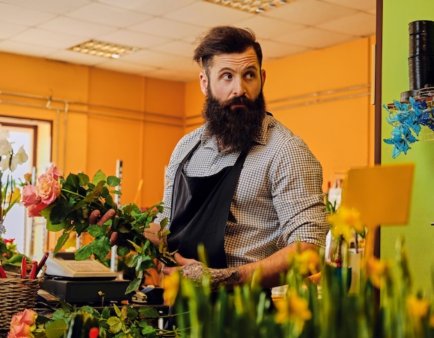 Free photo the bearded stylish flower seller holds pink roses in a market shop.