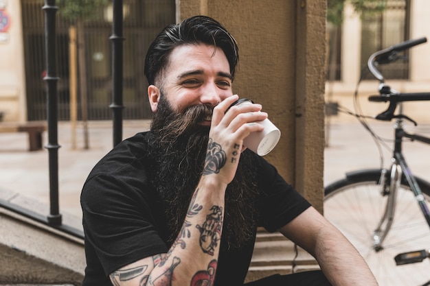 Free Photo bearded young man drinking the takeaway coffee