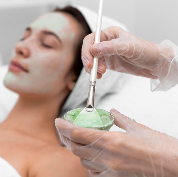 Beautician applying face mask on female client