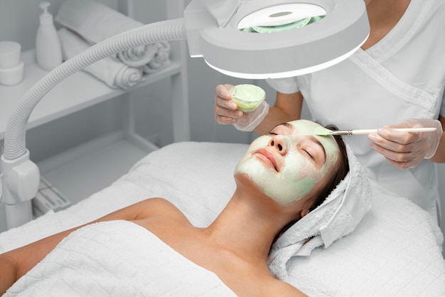 Beautician applying face mask on female client