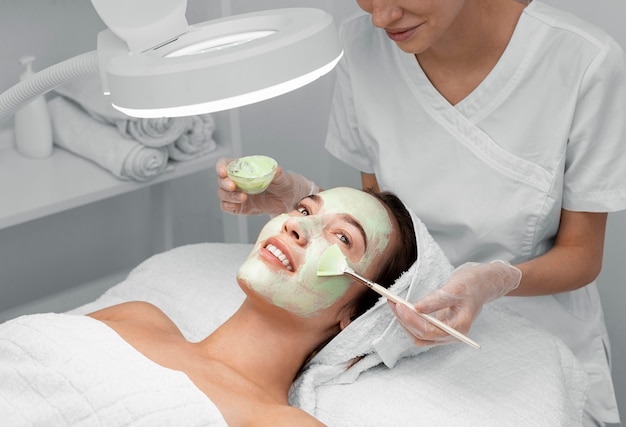 Beautician applying face mask on female client