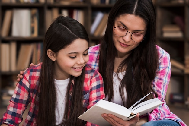 Beautiful adult woman and young girl reading a book