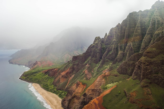 Beautiful aerial shot of the coast of Napali with clear beautiful water and steep rocks