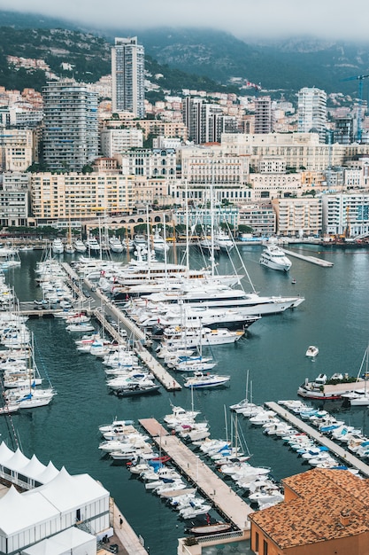 Beautiful aerial shot of a dock with many parked ships and an urban city in the background