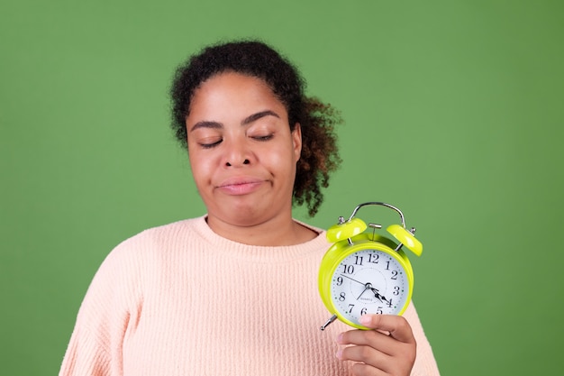 Beautiful african american woman on green wall with alarm clock angry tired  unhappy