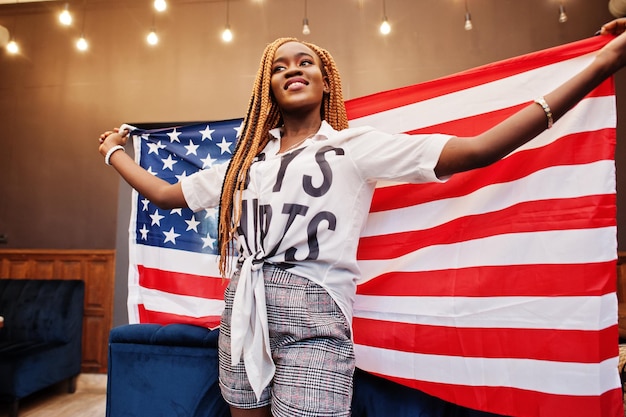 Free photo beautiful african woman in stylish casual clothes posing with usa flag at hands in office