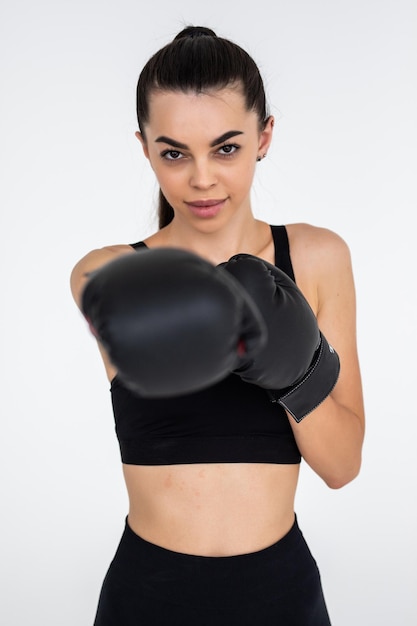 Beautiful angry sportswoman in boxing gloves in white background