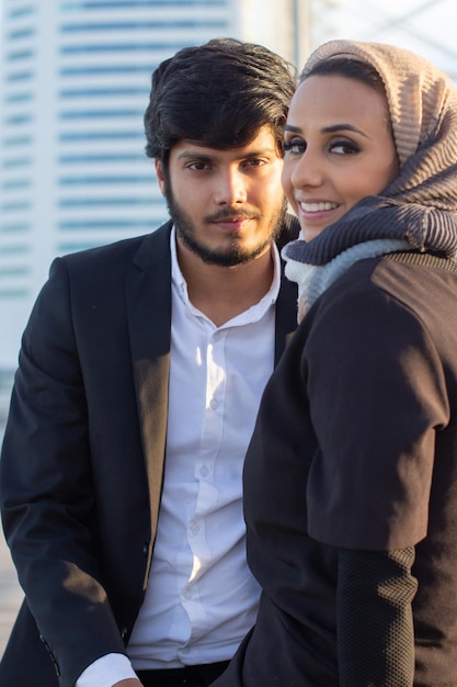 Free photo beautiful arabic couple spending time together. woman with covered head and bright make-up and man in suit sitting looking at camera. love, affection concept