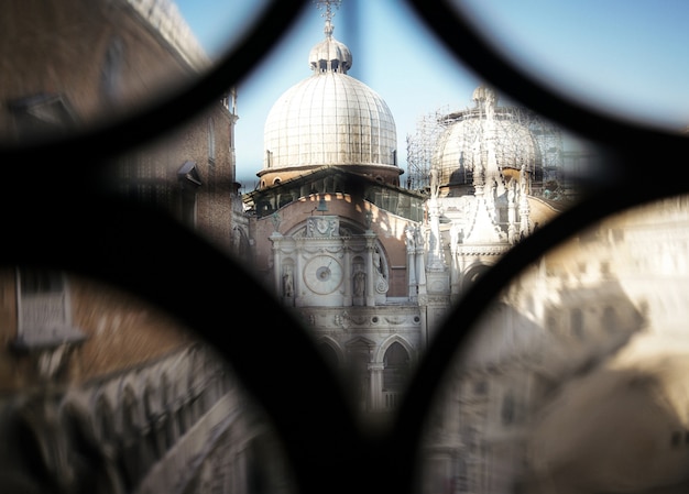 Beautiful architecture through a little hole of a window fence