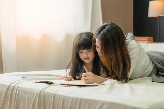 Free photo beautiful asian single mom with cute daughter happiness moment time teach homework homeschool ideas concept house background