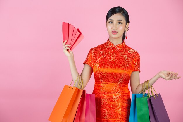 Beautiful Asian woman happy smile and shopping in chinese new year on pink background.