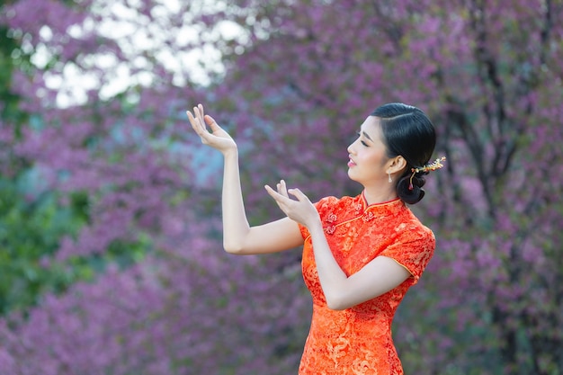 Beautiful Asian woman happy smile and show something to you in chinese new year on pink background.