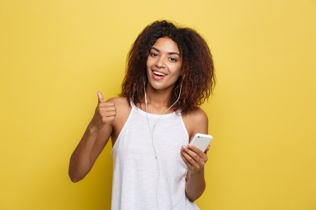 Beautiful attractive African American woman posting play with her curly afro hair. Yellow studio background. Copy Space.