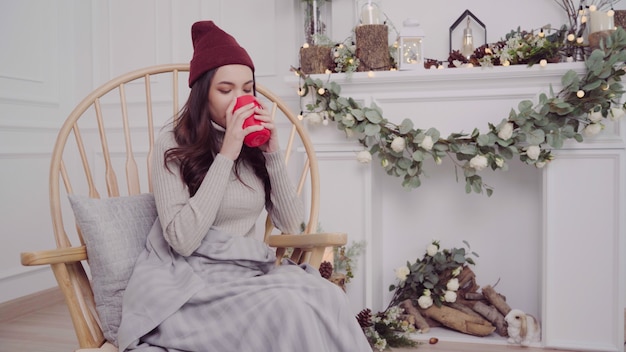 Beautiful attractive Asian woman holding a warm cup of coffee or tea while lying on chair 