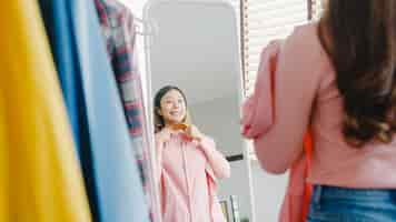 Free photo beautiful attractive lady choosing clothes on clothes rack dressing looking herself in mirror in bedroom at house.