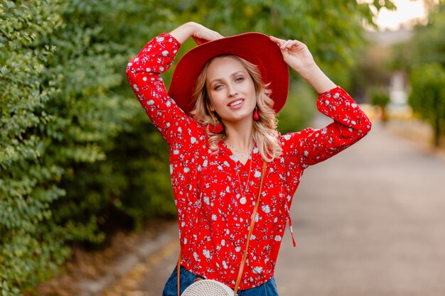 Beautiful attractive stylish blond smiling woman in straw red hat and blouse summer fashion outfit