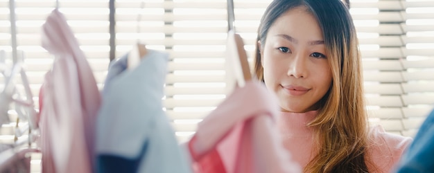 Beautiful attractive young lady choosing her fashion outfit clothes in closet at house or store.