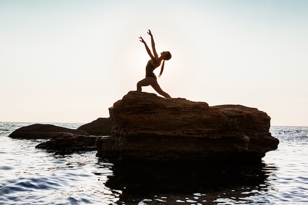 Free photo beautiful ballerina dancing, posing on rock at beach, sea views.