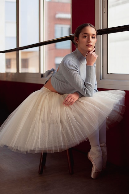 Free Photo beautiful ballerina in tutu skirt posing next to window