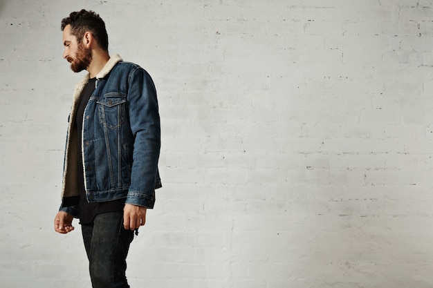 Free Photo beautiful bearded man weared shearling denim jacket and black blank clothes isolated on white brick wall in club