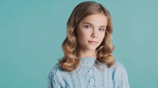 Beautiful blond haired teenager girl intently looking in camera posing over colorful background Studio shot