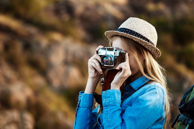 Beautiful blonde female photographer taking picture of canyon landscape