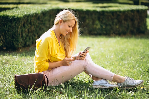 Free Photo beautiful blonde sitting on grass and working on laptop