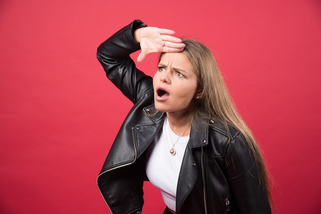 Beautiful blonde woman looking far away with hand over head