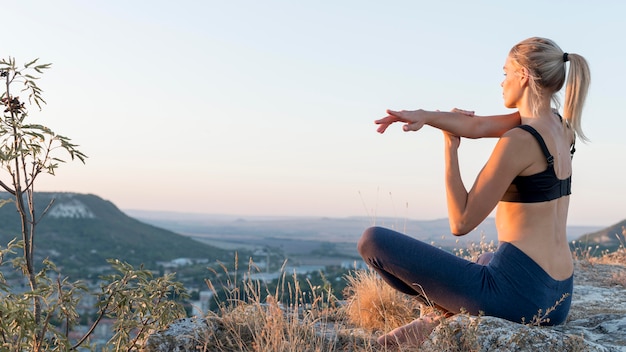 Beautiful blonde woman practicing yoga outdoors