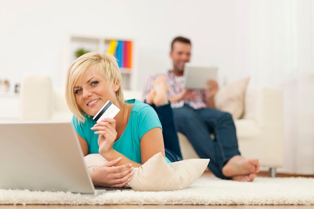 Beautiful blonde woman relaxing at home with laptop and credit card