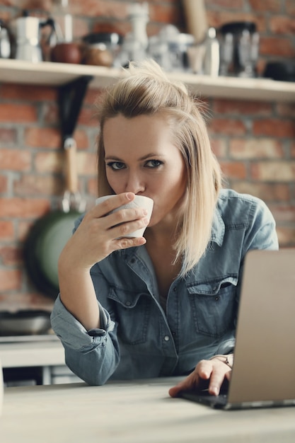 Beautiful blonde woman with coffee cup and laptop